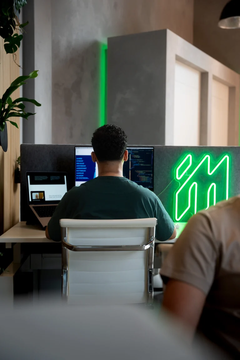 Collega's achter hun schermen naast het neonlogo