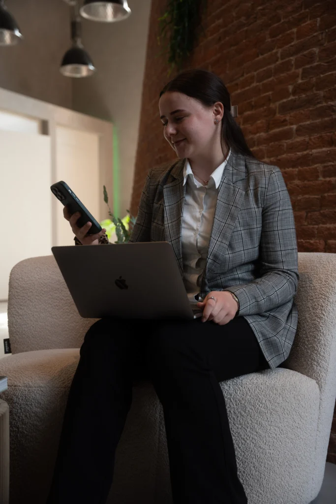 Collega werkt met laptop en telefoon vanuit een fauteuil