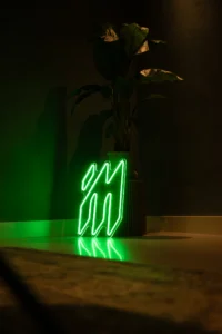 Groen neonlogo van Innovatie Media naast een plant