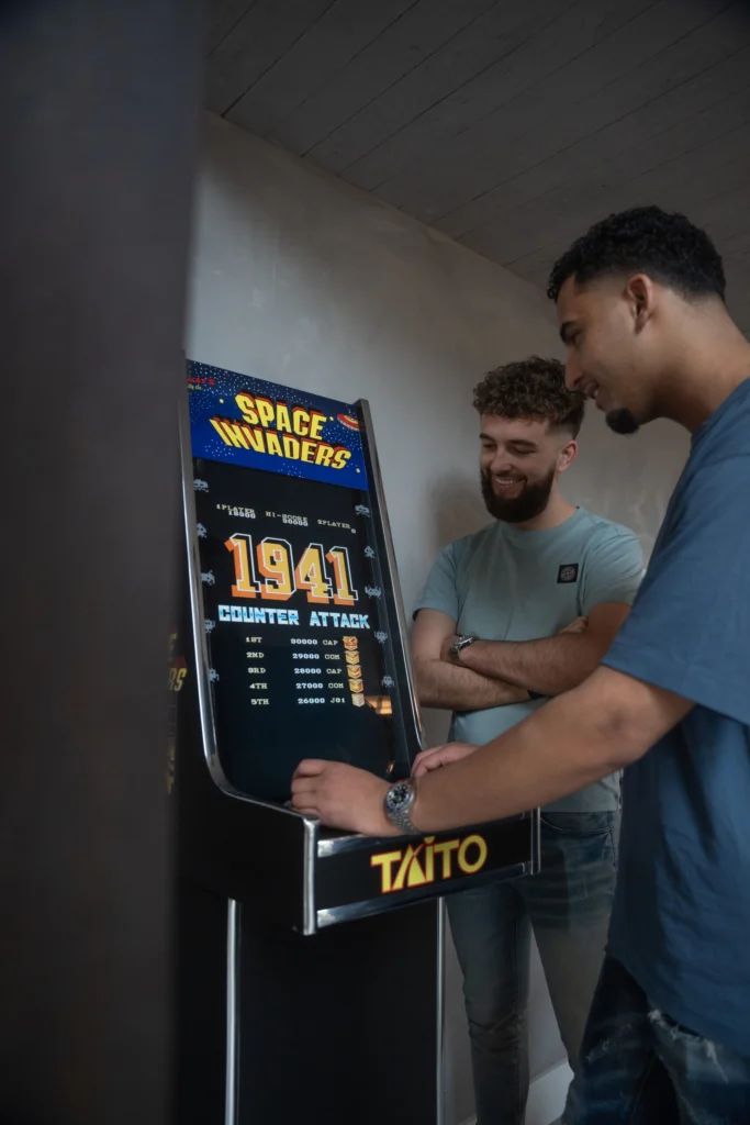 Twee collega's bij de Space Invaders-speelkast